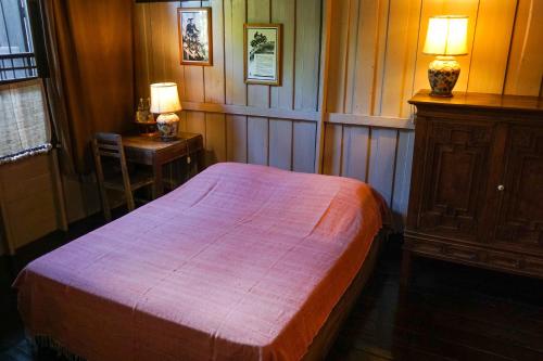 a bedroom with a bed and a table with a lamp at The Riverside Guest House in Lampang