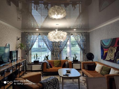 a living room with a couch and a table and a chandelier at Country house Dom pod sosnami in Ulybyshevo