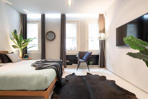 a bedroom with a bed and a chair and windows at OFFICINE CAVOUR Piazza Cavour in Padova
