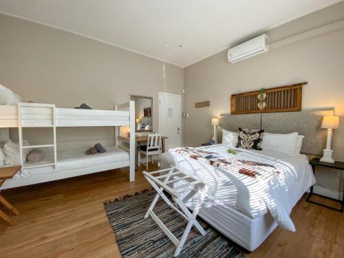a bedroom with a bed and bunk beds and a desk at De Akker Guest House Oudtshoorn in Oudtshoorn