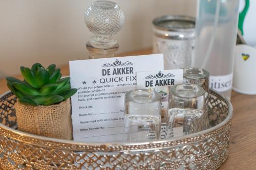 a tray with glasses and a sign on a table at De Akker Guest House Oudtshoorn in Oudtshoorn