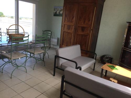 ein Wohnzimmer mit einem Tisch, Stühlen, einem Tisch und einem Glastisch in der Unterkunft Maison cozy in Le Pin