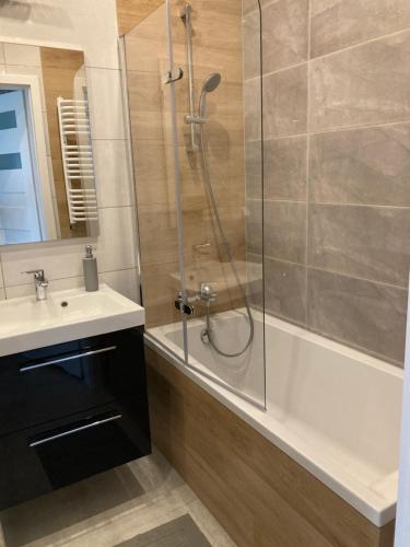 een badkamer met een douche, een wastafel en een bad bij Apartament Fabryczna 35 in Białystok