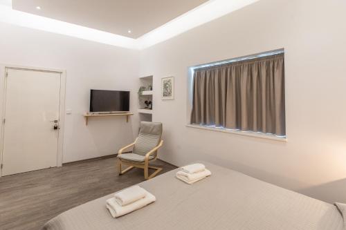 a bedroom with a bed and a chair and a television at Rooms - Unique staying in Paphos Centre in Paphos City