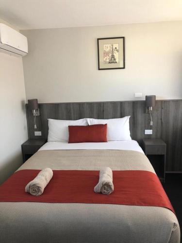 a bedroom with a large bed with two towels on it at Bradman Motor Inn in Cootamundra