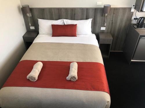 a bedroom with a large bed with two towels on it at Bradman Motor Inn in Cootamundra