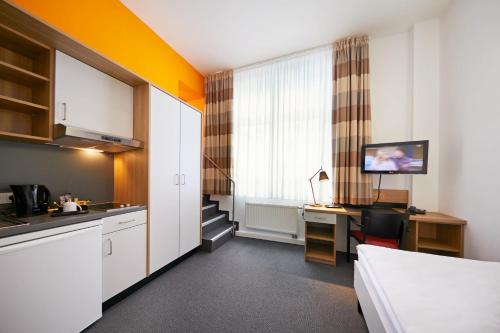 a room with a kitchen with a desk and a table at Townhouse Düsseldorf in Düsseldorf