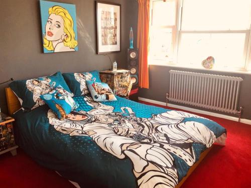 een slaapkamer met een bed met een tekenfilmontwerp bij Pop Art Pad heart of Old Town with parking! in Hastings