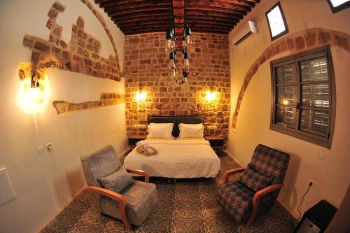 a bedroom with a bed and two chairs at Salah Aldin House in Acre