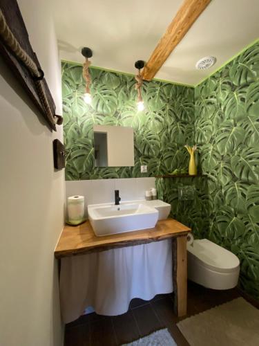 a bathroom with a sink and green leafy wallpaper at Siedlisko Odpoczynkowo in Nowosiółki