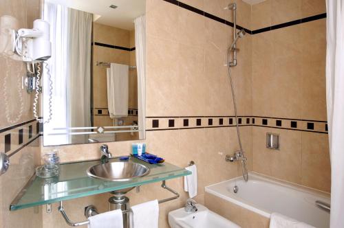 a bathroom with a sink and a bath tub at Evenia Rocafort in Barcelona