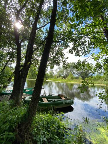a boat is parked on the side of a river at Siedlisko Odpoczynkowo in Nowosiółki