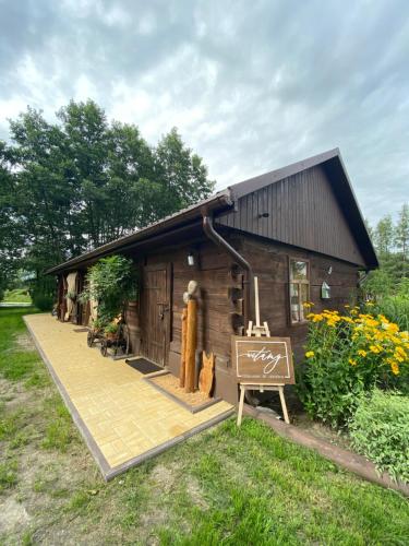 a small wooden cabin with a sign in front of it at Siedlisko Odpoczynkowo in Nowosiółki