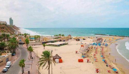 una spiaggia con persone e ombrelloni e l'oceano di Hotel Alma - Near The Sea a Netanya