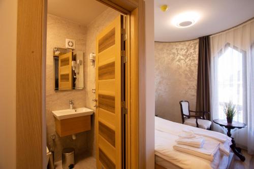 a bathroom with a sink and a bed and a sink at Hotel Vrbak ND in Novi Pazar