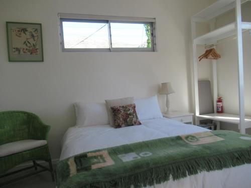 a bedroom with a bed and a chair and a window at Royal@Sea2 in Muizenberg