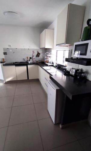 a kitchen with white cabinets and a black counter top at Guest House "Villa Klara Eilat" Heated pool and sauna all year round in Eilat
