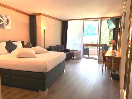 Hotel Quellenhof Leukerbad في لوكرباد: فندق غرفه بسرير وصاله