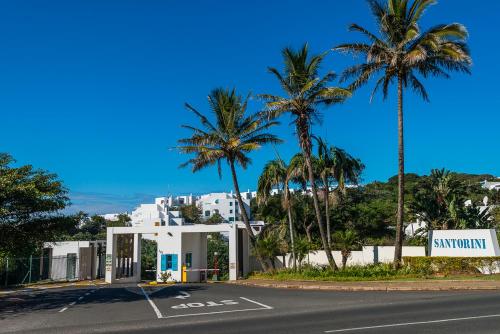a street with palm trees and a white building at Santorini - Akrotiri 3 in Ballito
