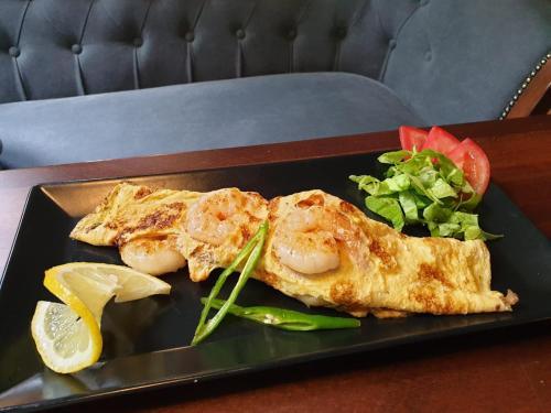 een zwart bord met twee stukken vis en een salade bij Corso Apartments B&B in Focşani