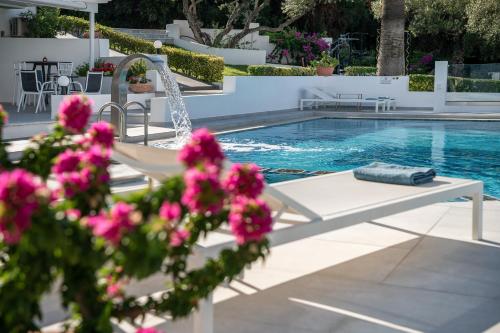 a swimming pool with pink flowers in the foreground at Villa Life in Agia Marina Nea Kydonias