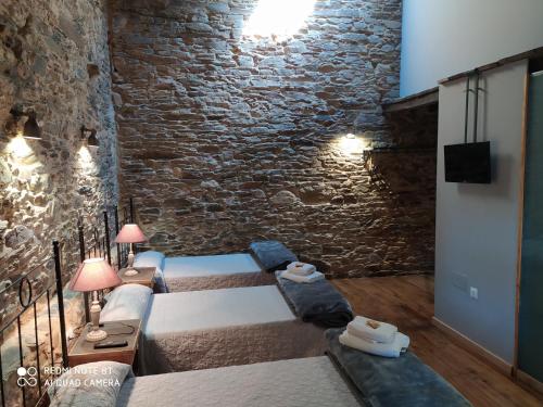 a bedroom with two beds and a brick wall at Albergue Atrio in Treacastela