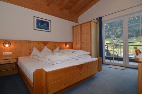 um quarto com uma cama de madeira e uma grande janela em Garni Dorfblick em Ischgl