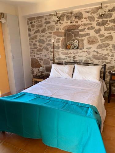 a bed in a room with a stone wall at VERANDA BLUE - POROS in Poros