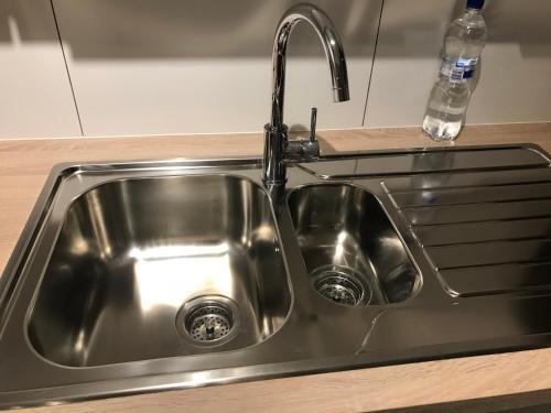 a stainless steel kitchen sink with a faucet at Lumineux appartement in Louvain-la-Neuve