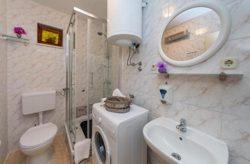 een badkamer met een wastafel, een toilet en een spiegel bij Guesthause Arbor in Split