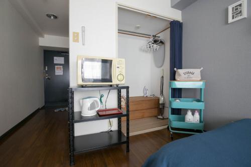 a room with a bed and a tv on a shelf at Wings Hakata in Fukuoka