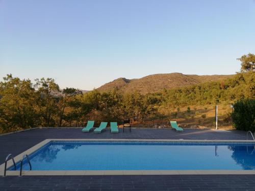 a swimming pool with chairs and a view of a mountain at Quinta dos Carvalhais - Serra da Estrela in Fornos de Algodres