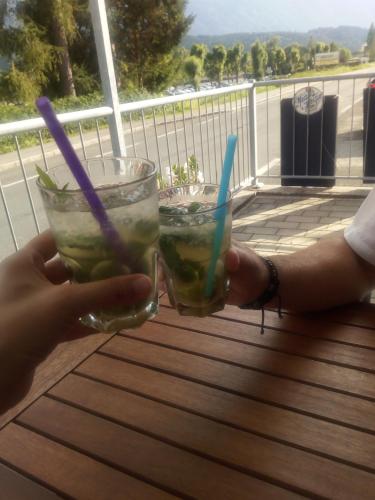 two people holding drinks on a table on a balcony at Landhaus Tirol in Presseggersee