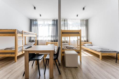 a room with bunk beds and a table and a desk at Hostel Północna 61 in Sosnowiec