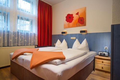 a bedroom with a large bed with an orange blanket on it at H&H Studio-Apartments im Zentrum jedes Apartment mit Küchenzeilen - 24h Check In in Greifswald