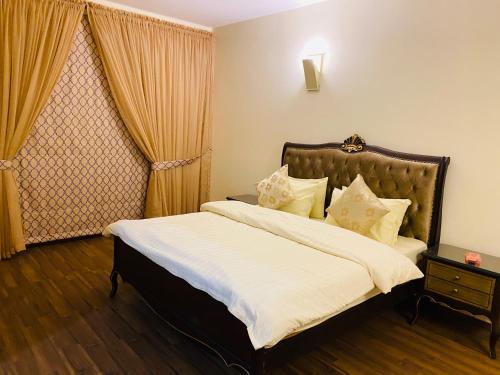 a bedroom with a bed with white sheets and a window at Royal Two Bed Luxury Apartment Gulberg in Lahore