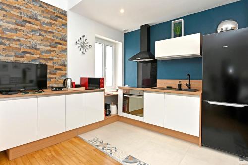 une cuisine avec des placards blancs et un mur en briques dans l'établissement HYPERCENTRE - Calme et lumineux. AufildeLorient, à Lorient