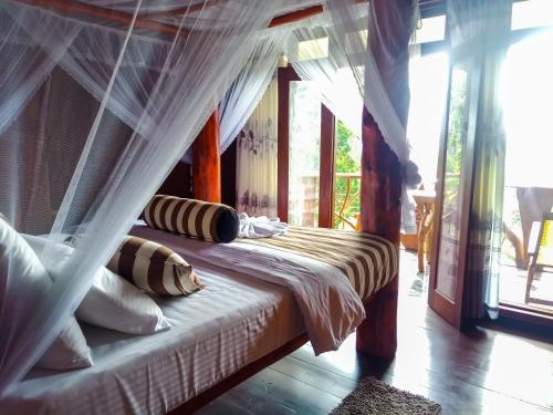a bedroom with a bed with a mosquito net at CHILL Wood ELLA in Ella