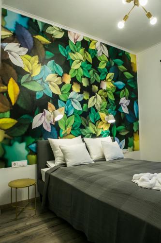 a bedroom with a wall with a flower mural at Marusius Apartmanház in Makó