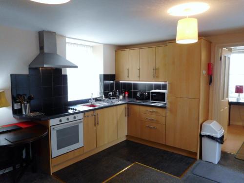 eine Küche mit Holzschränken und einem Herd mit Backofen in der Unterkunft DairyCottage, 5, TELFORD MEWS BEATTOCK in Moffat