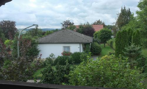 ein weißes Haus in einem Garten mit Bäumen und Sträuchern in der Unterkunft wohnung oben Steiger in Bad Birnbach