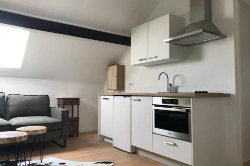 a kitchen with white cabinets and a couch in a room at Authentic Stays - 4p-apartment in Eijsden