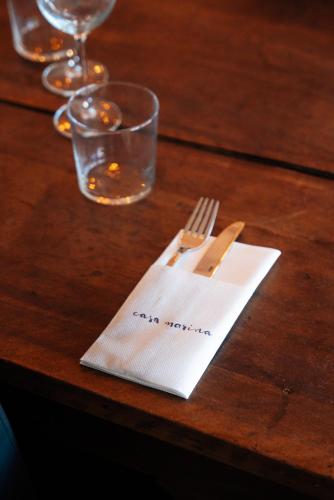 a wooden table with a napkin with a fork and knife at Hôtel Casa Marina in Saintes-Maries-de-la-Mer