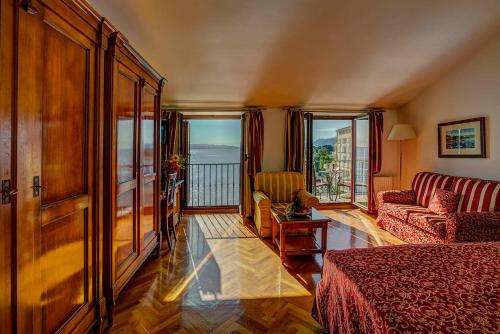 a hotel room with a bed and a couch and windows at Hotel Miramar in Opatija