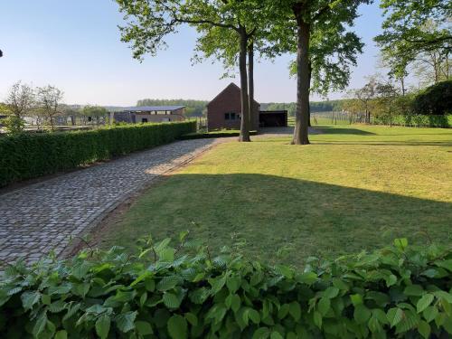 a brick path in a park with trees and a barn at Lemen huis Houwaart in Tielt