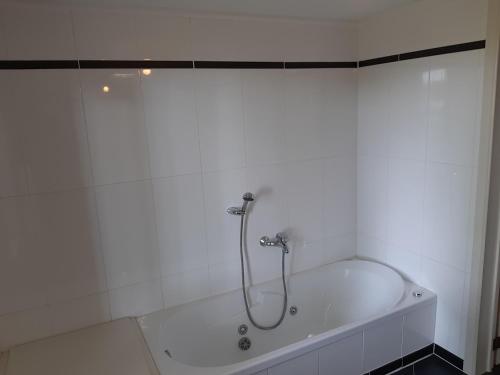 a bath tub with a shower in a bathroom at Lemen huis Houwaart in Tielt