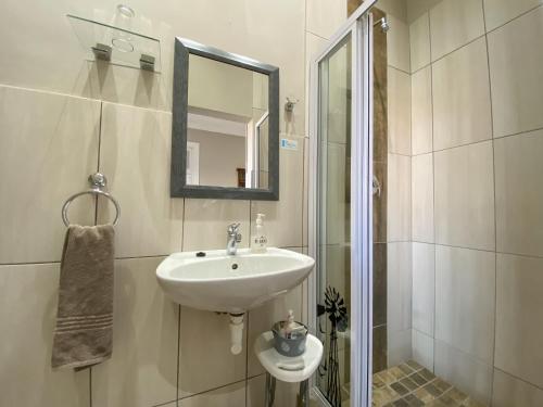 a white bathroom with a sink and a mirror at De Akker Guest House Oudtshoorn in Oudtshoorn
