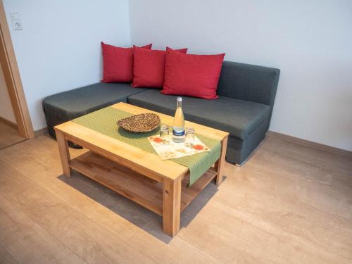 a couch with red pillows and a table with a bottle at Hotel - Restaurant - Metzgerei Sonne in Loffenau