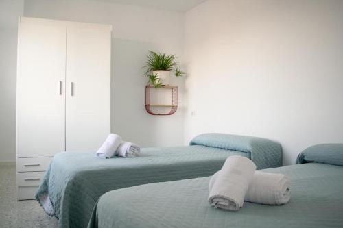 una habitación con 2 camas y una planta en la pared en Alojamientos Teatro, en Porcuna