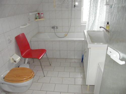 ein Badezimmer mit einem WC, einem Waschbecken und einem roten Stuhl in der Unterkunft Ferienwohnung ULLABRU in Ascheffel